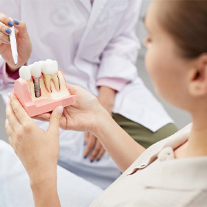 Dentist showing a dental implant model to a patient