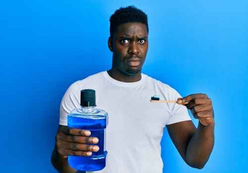 Black male against blue background holding blue mouthwash and a toothbrush
