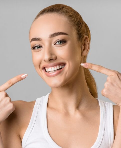 Woman pointing to smile after cosmetic dentistry