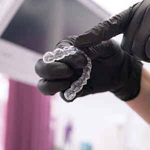 dentist with black gloves pointing to clear aligners
