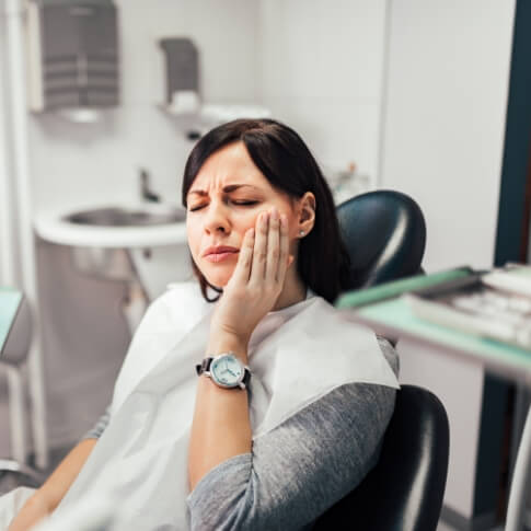 Woman holding cheek before emergency dentistry