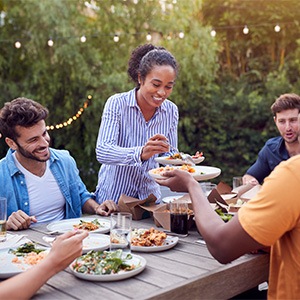 Group of friends smiling while enjoying meal outside