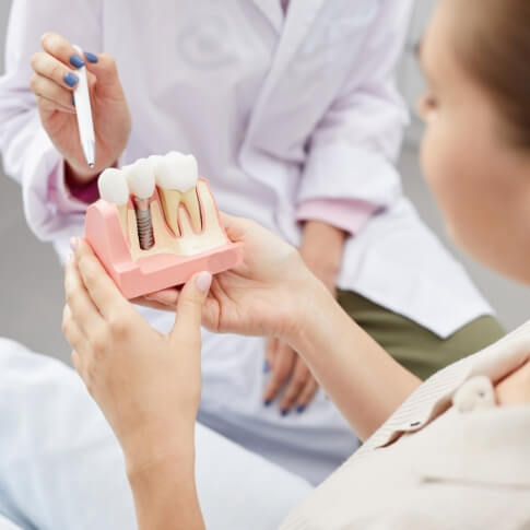 A patient holding an enlarged dental implant model