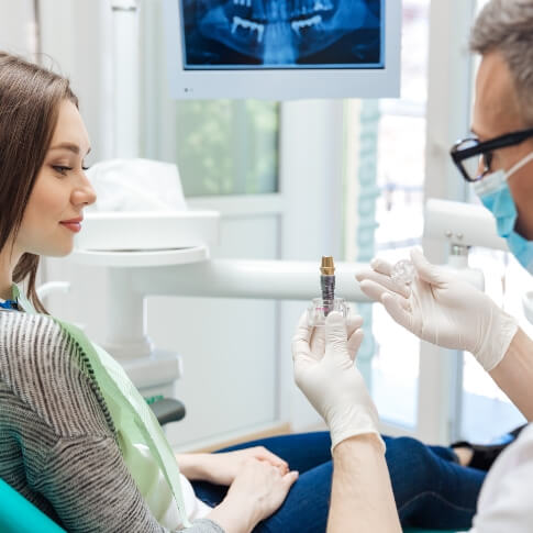 Dentist showing a dental implant to a patient