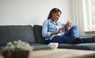 Woman smiling while reading book on couch