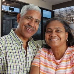 Older man and woman smiling in reception area of dental office