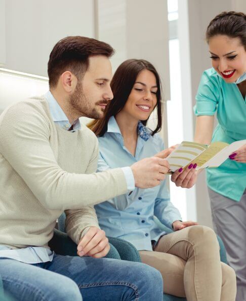 Dental team member and dentistry patients discussing dental insurance