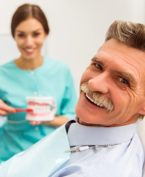 Older man smiling after replacing missing teeth