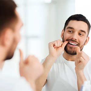 Patient smiling while flossing his teeth