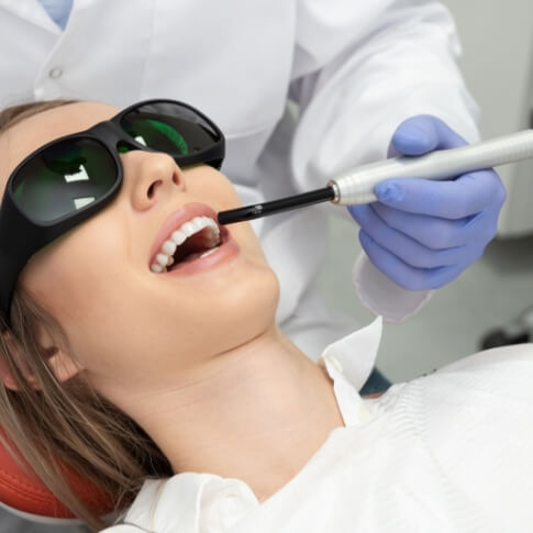 Dentist providing laser diagnosis and dental treatment
