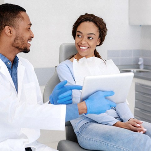 Dentist and patient smiling while reviewing information on tablet