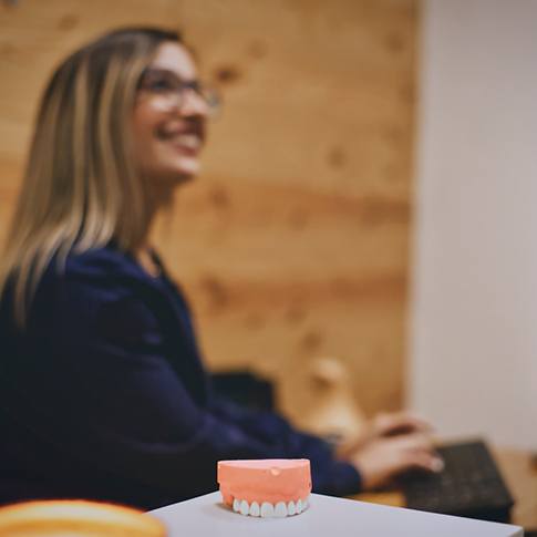 Closeup of model of teeth on smiling dental receptionist's desk