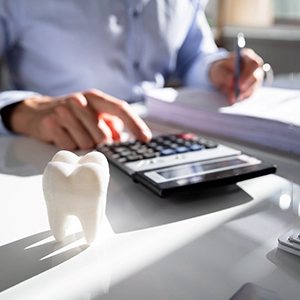Person using calculator at desk with prop tooth