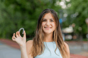 a patient smiling and holding their Candid clear aligner
